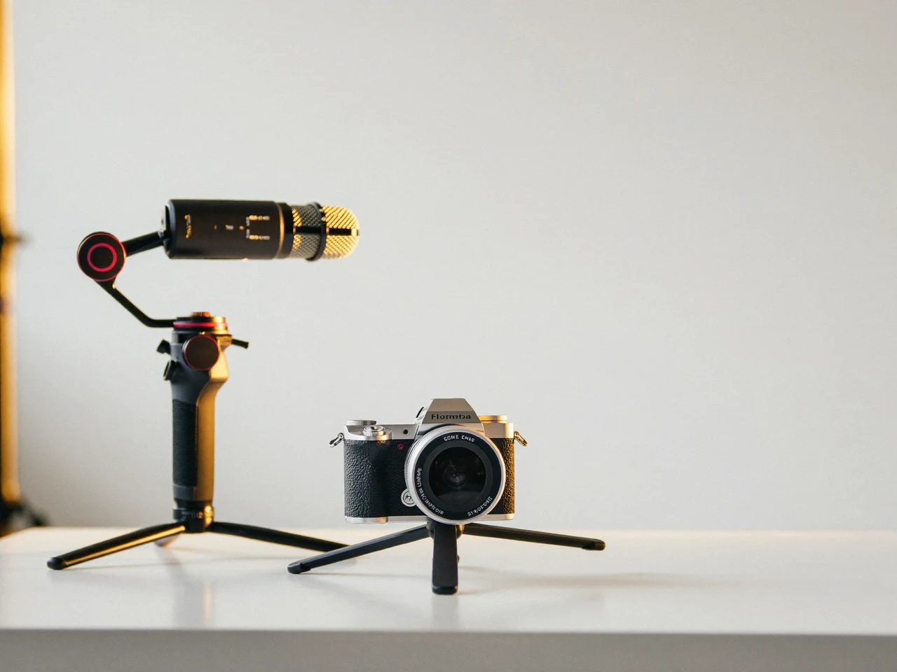 Kamera auf Stativ, daneben Gimbal und Mikrofon, auf einem hellen Studiotisch