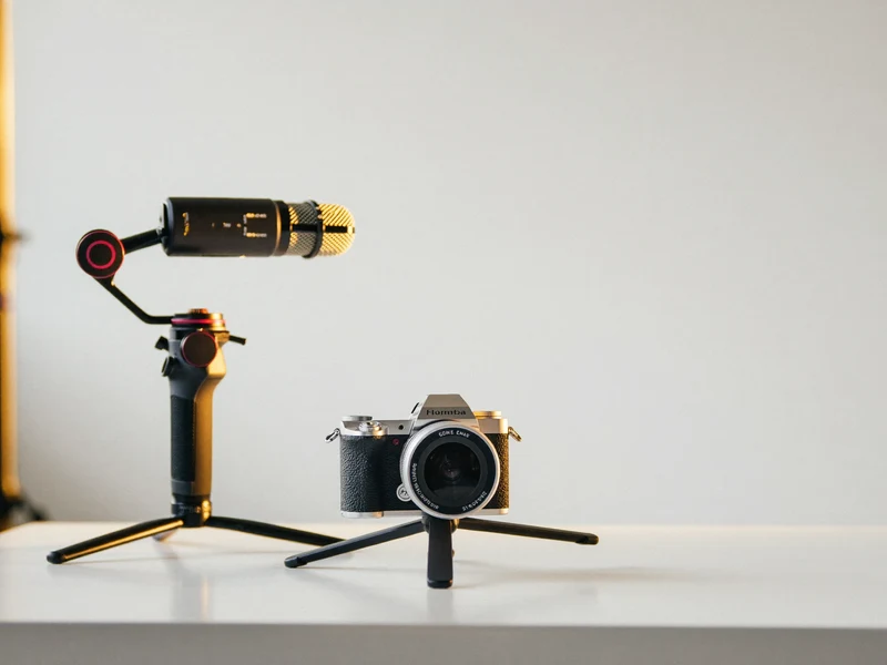 Kamera auf Stativ, daneben Gimbal und Mikrofon, auf einem hellen Studiotisch